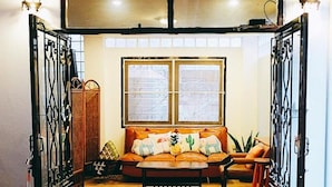 Una sala de estar acogedora con un sofá, dos ventanas y cojines decorativos.