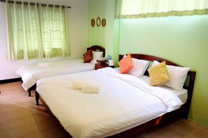 Two single beds with white linens and pillows, a bedside table, and a small table with refreshments.
