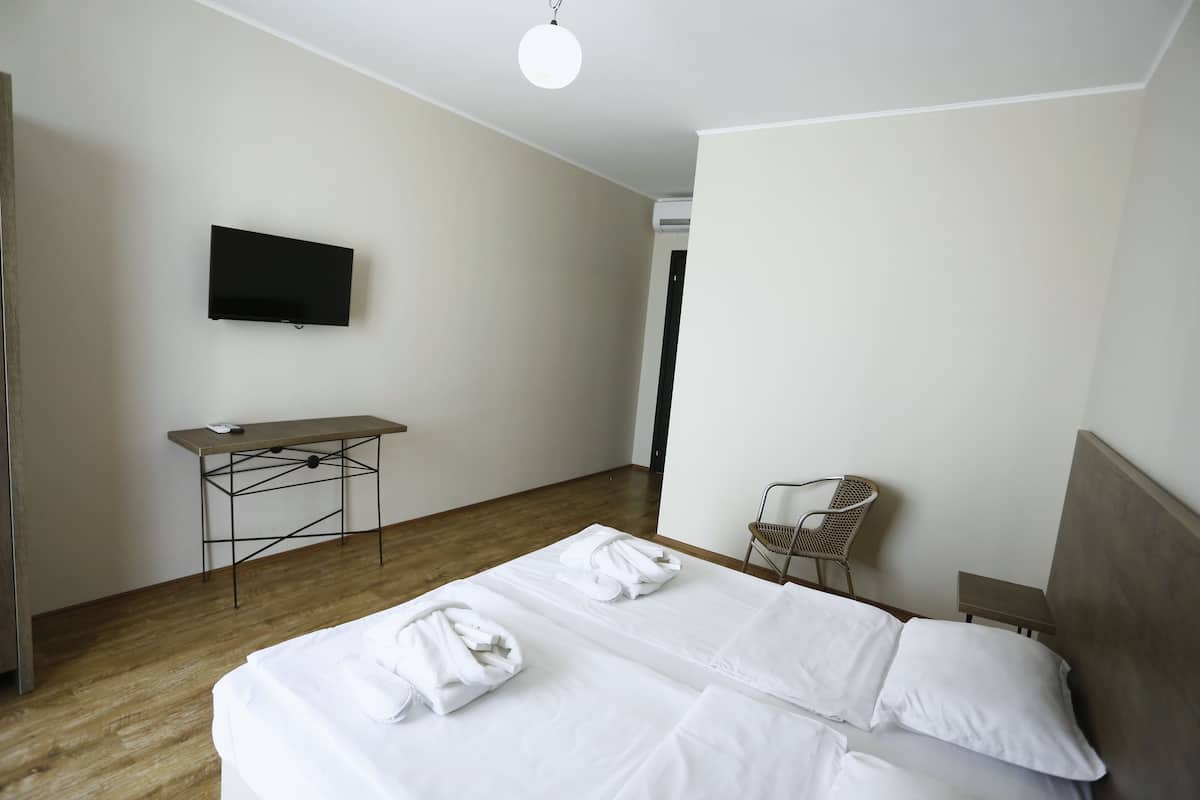 A hotel room with a bed, a desk, a chair, and a TV.