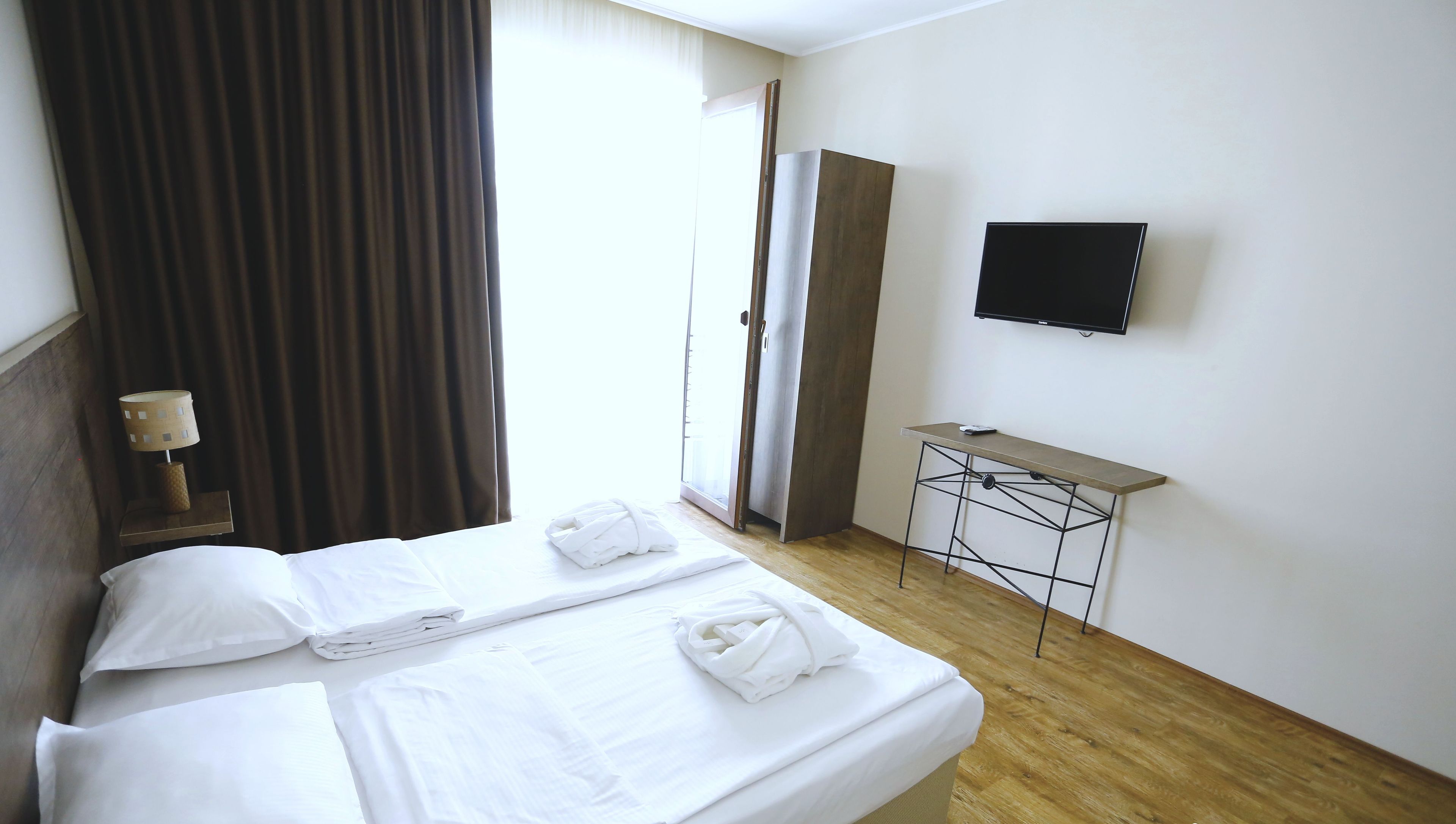 Een hotelkamer met een bed, een bureau, een televisie en een raam met gordijnen.
