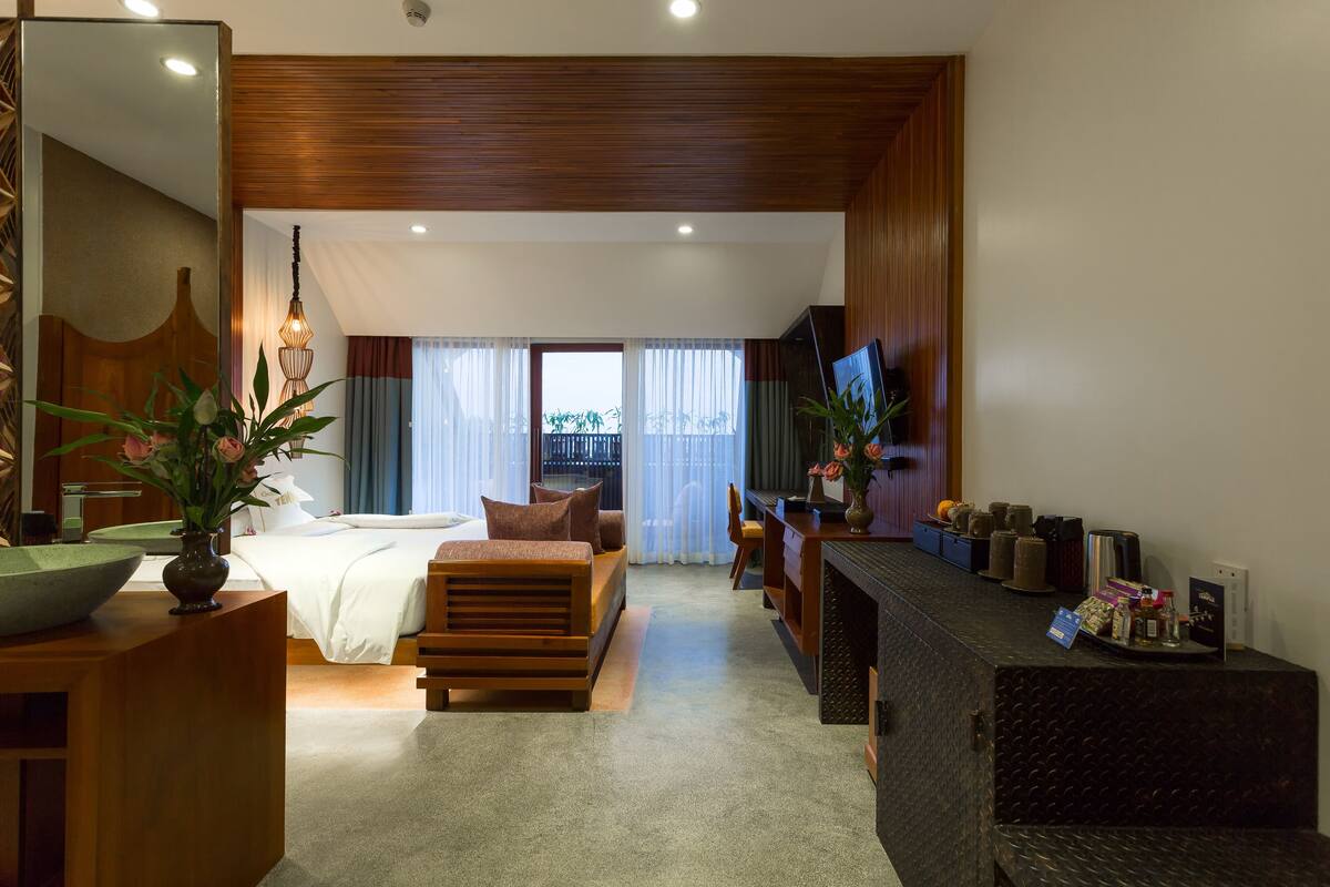 A hotel room with a bed, a seating area, a desk, and a TV.