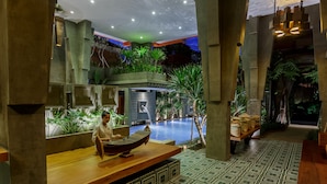 Zona de recepción con mostrador de madera, piscina y plantas de interior.