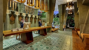 Una zona de recepción con un mostrador de madera largo, varias sillas y un piso con diseño.