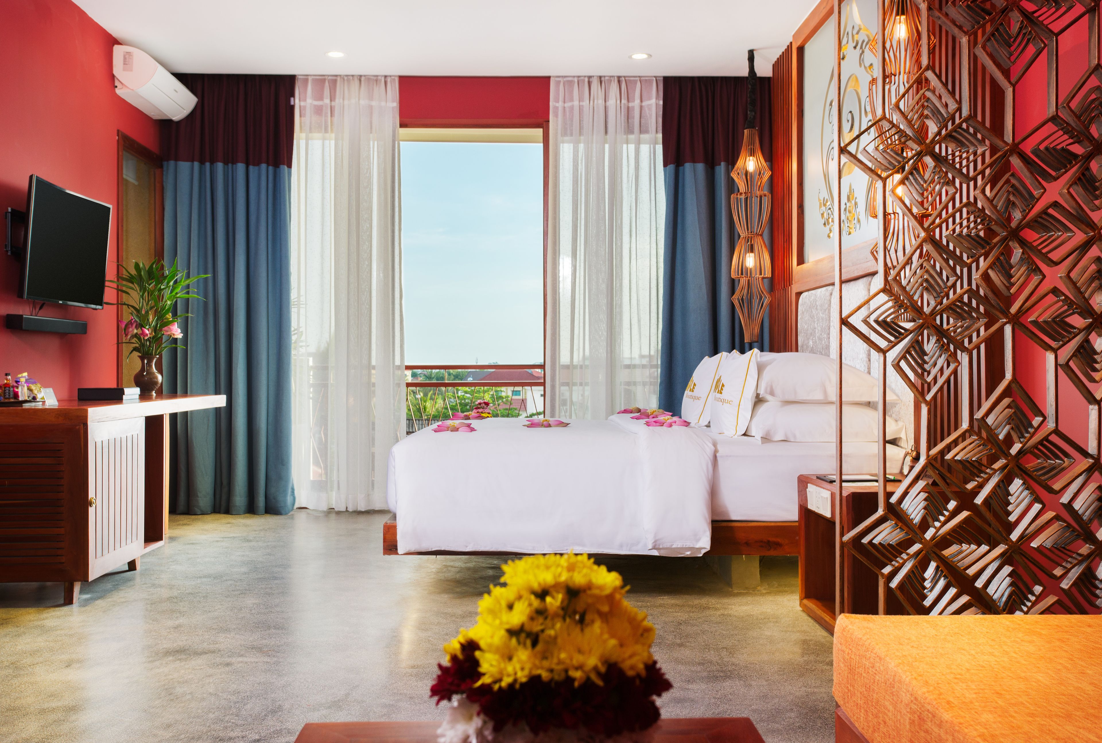 Habitació d'hotel amb llit, escriptori, televisió i un mur decoratiu.