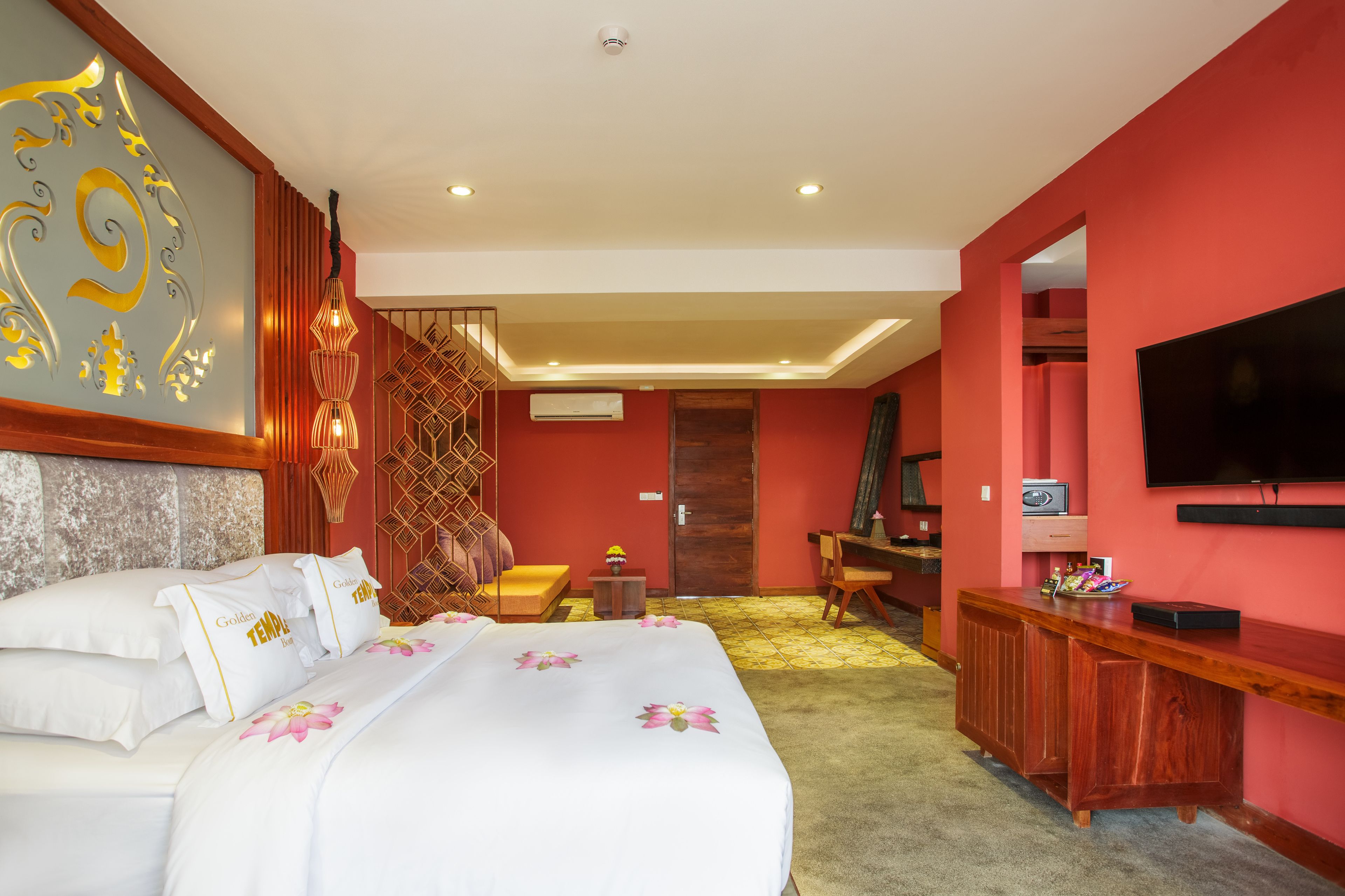 A hotel room with a large bed, a desk, a TV, and a decorative wall.