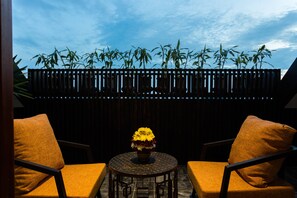 Une pièce avec une table ronde, deux chaises et un pot de fleurs contenant des fleurs jaunes.