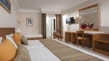 A hotel room with a large bed, a desk, a chair, a television, and a mirror.