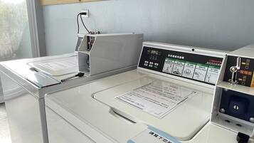 A modern laundry facility with a digital control panel, a white washing machine, and a drying machine.
