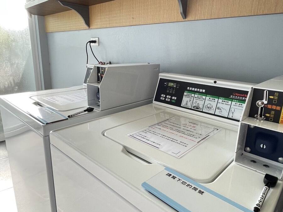 A modern laundry facility with a digital control panel, a white washing machine, and a drying machine.