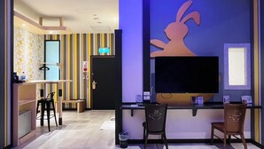 A modern hotel lobby with a large TV screen, a reception desk, and a seating area with two chairs. - Wei Feng Exquisite Motel Pintung Branch (Pingtung)