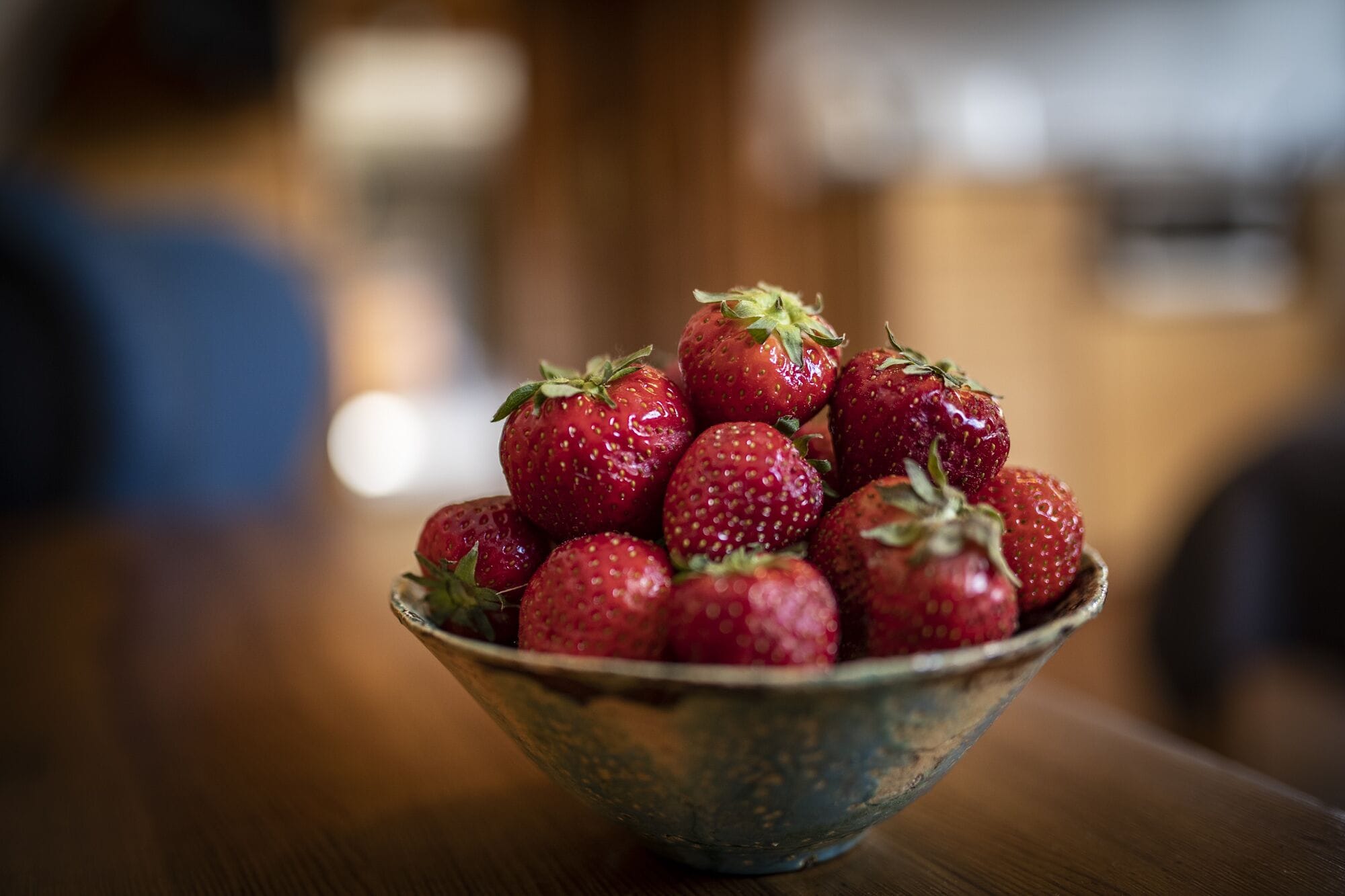 Un bol de fraises sur une table en bois.