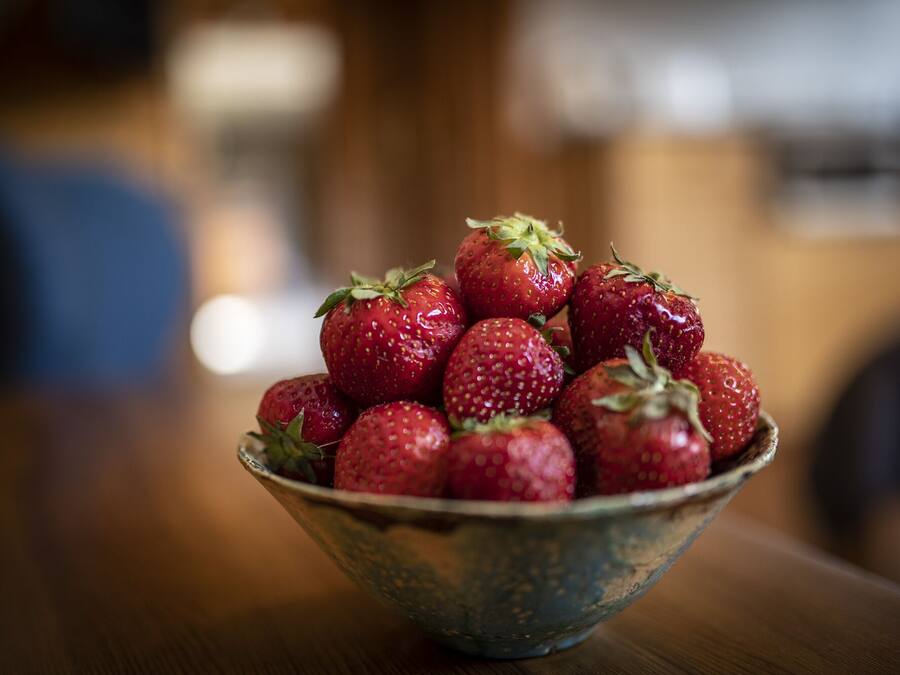 Un bol de fraises sur une table en bois.
