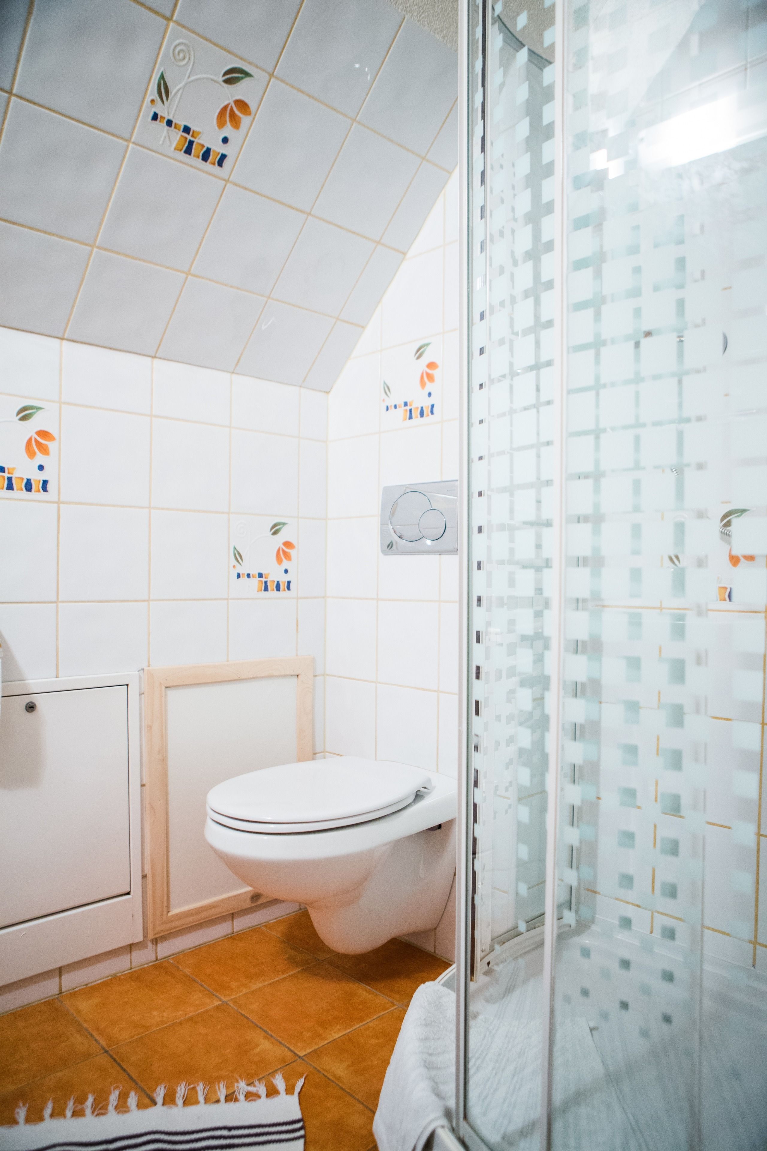 Une salle de bain avec des toilettes, une douche et des murs carrelés.