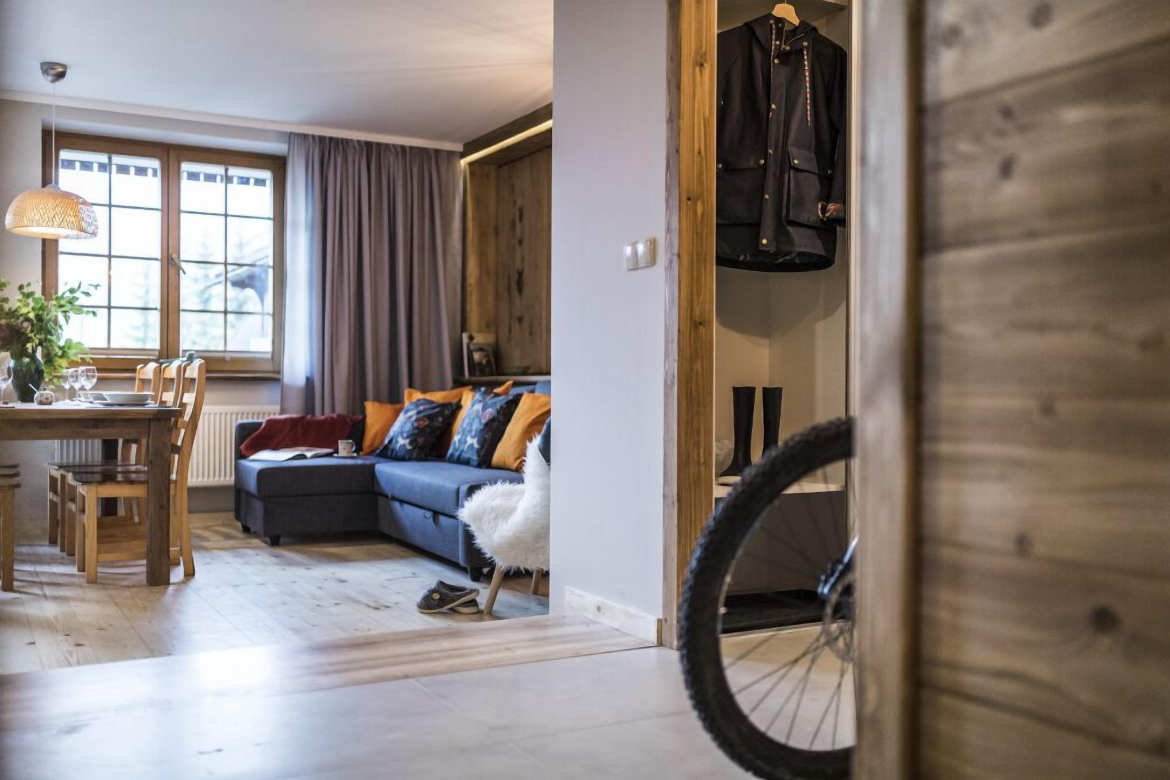 Un salon confortable avec un canapé, une table à manger et des chaises. Un vélo est partiellement visible au premier plan.