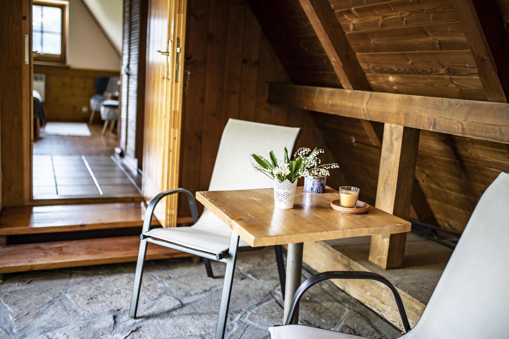 Un intérieur en bois avec une table et des chaises, une plante en pot et un verre de lait.
