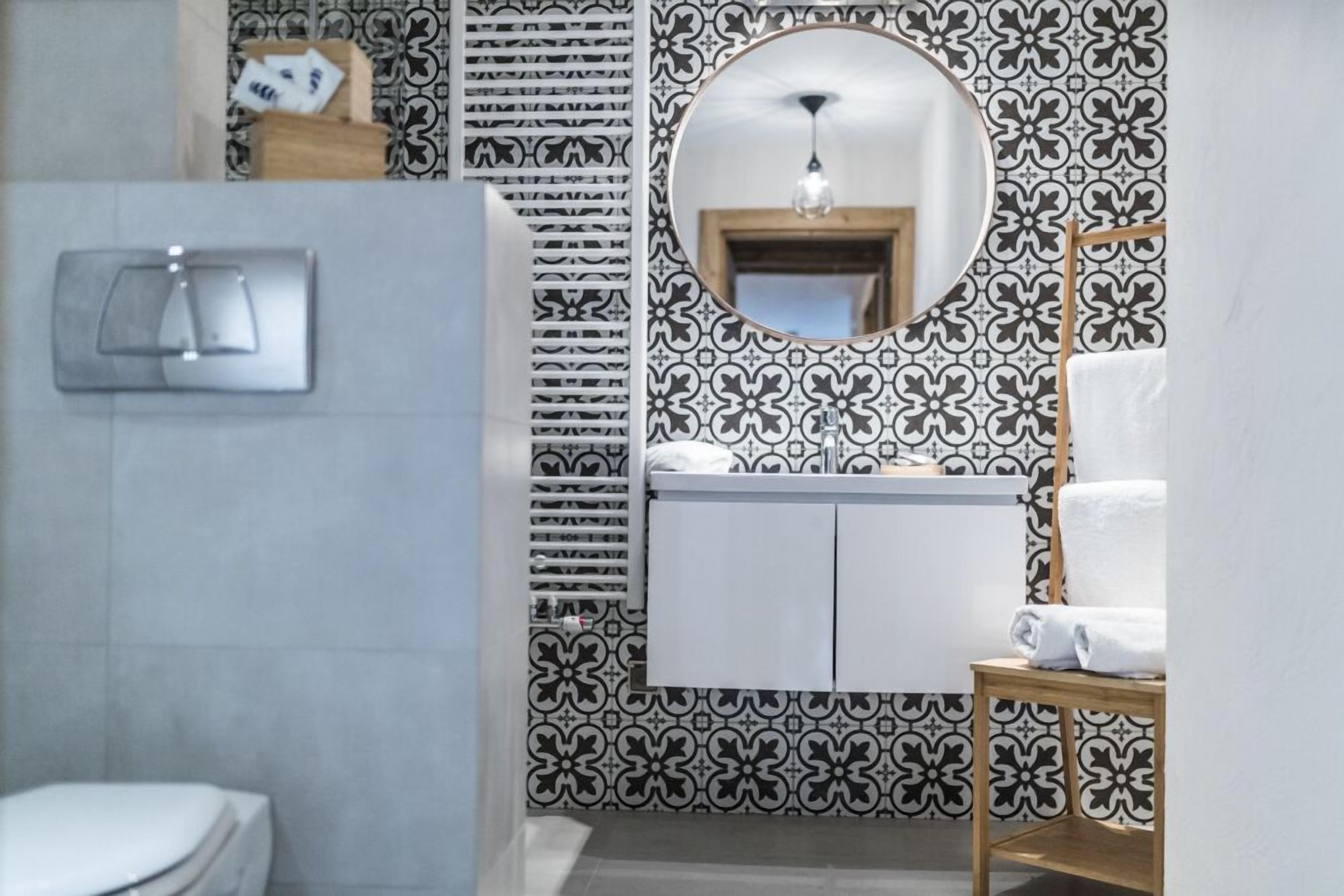 A bathroom with a white toilet, a sink with a mirror above it, and a patterned wall.