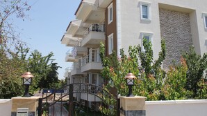 Un edificio de varios pisos con balcones, fachada de piedra y entrada con reja.