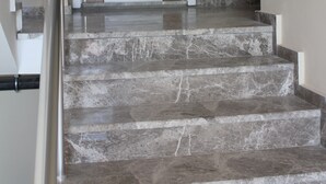 Una escalera con escalones de mármol que lleva a una puerta con panel de madera y manija de metal.