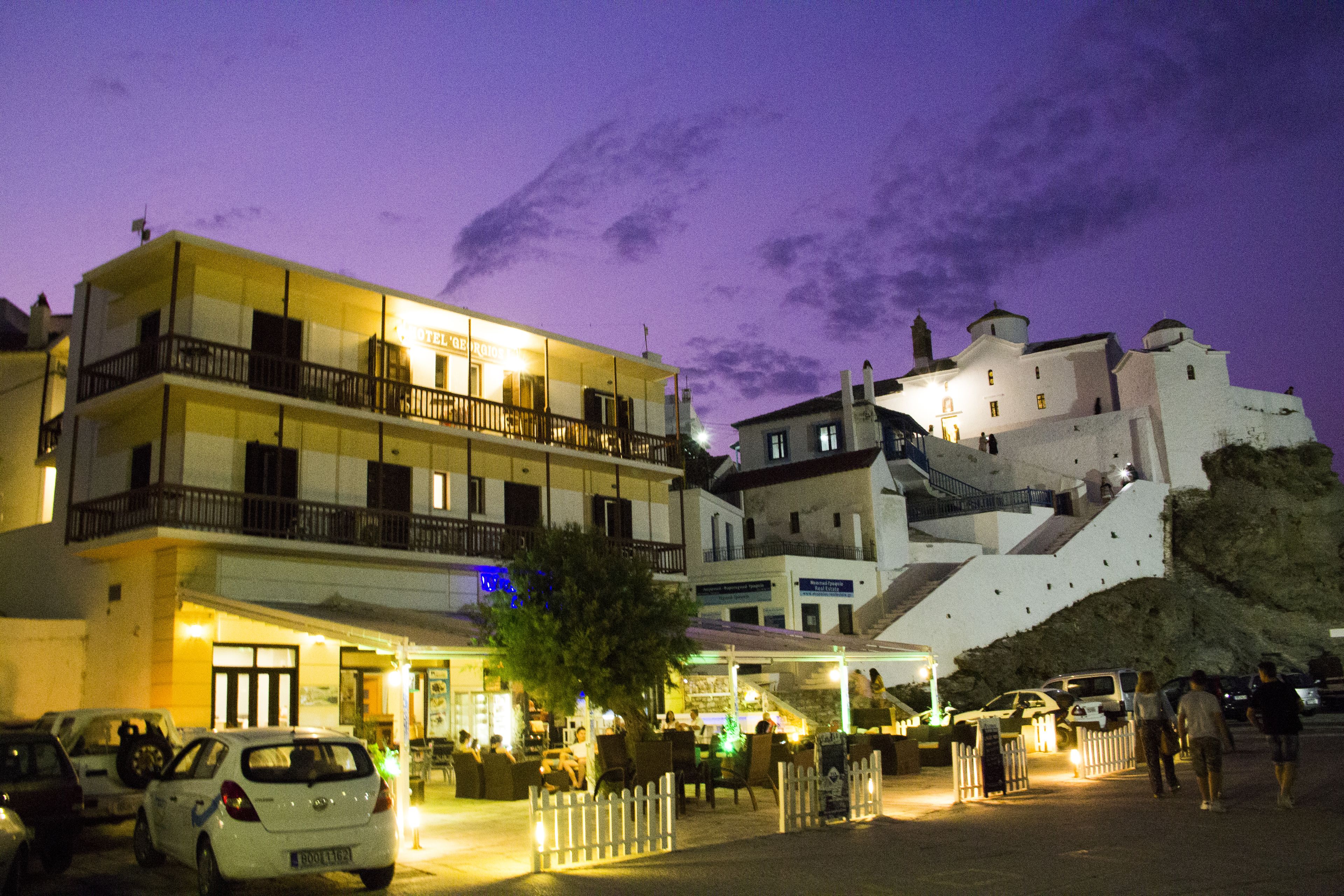 A hotel with multiple floors, outdoor seating, and a view of a historic building.