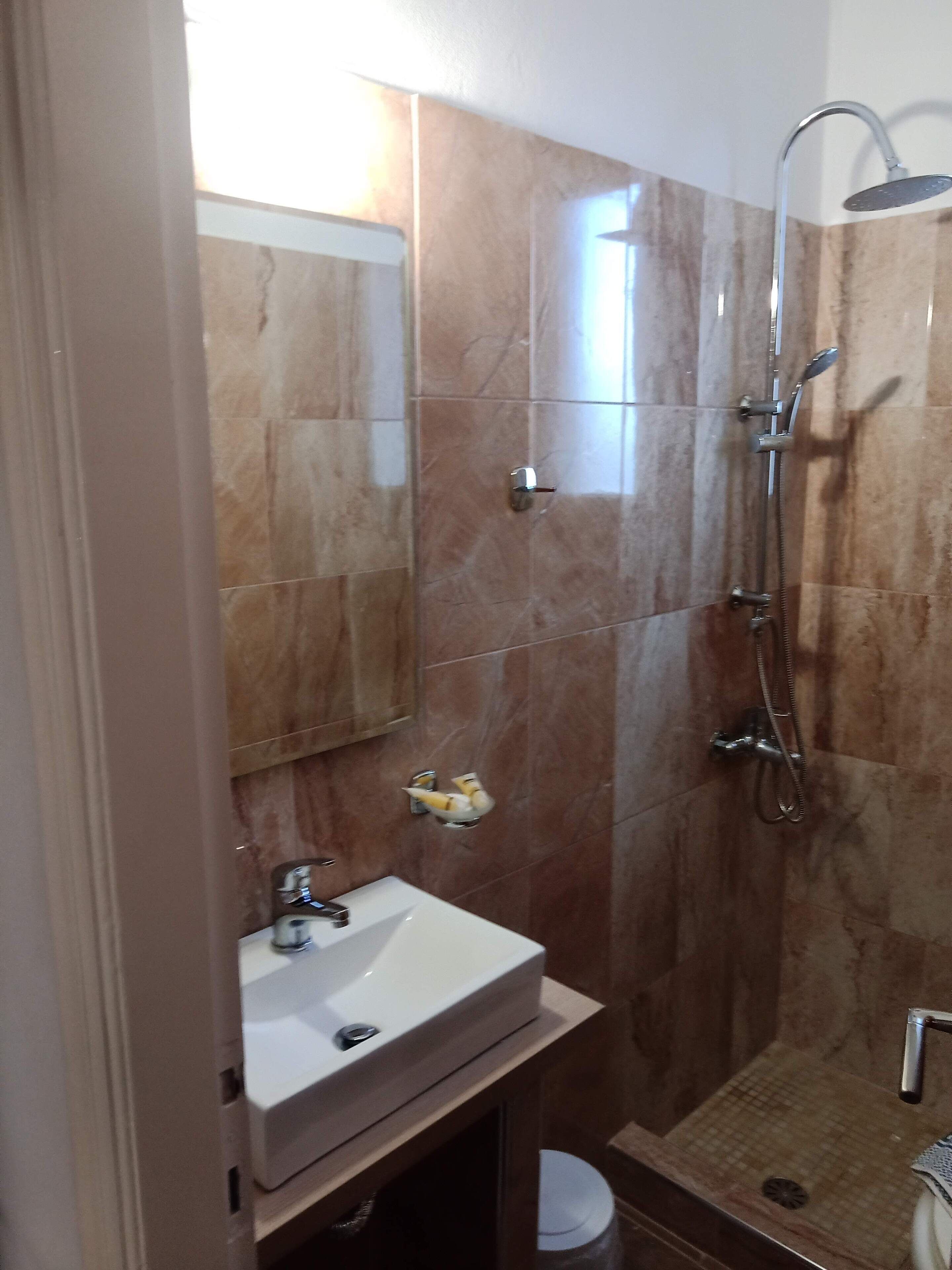 A bathroom with a shower, sink, and mirror.