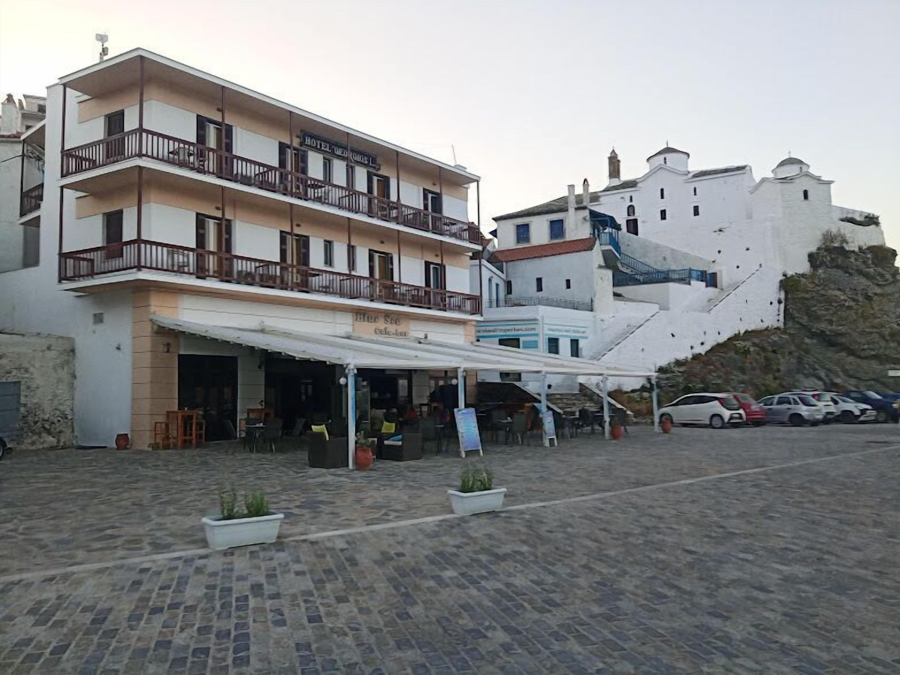 A hotel with a white facade, multiple balconies, and a covered outdoor seating area.