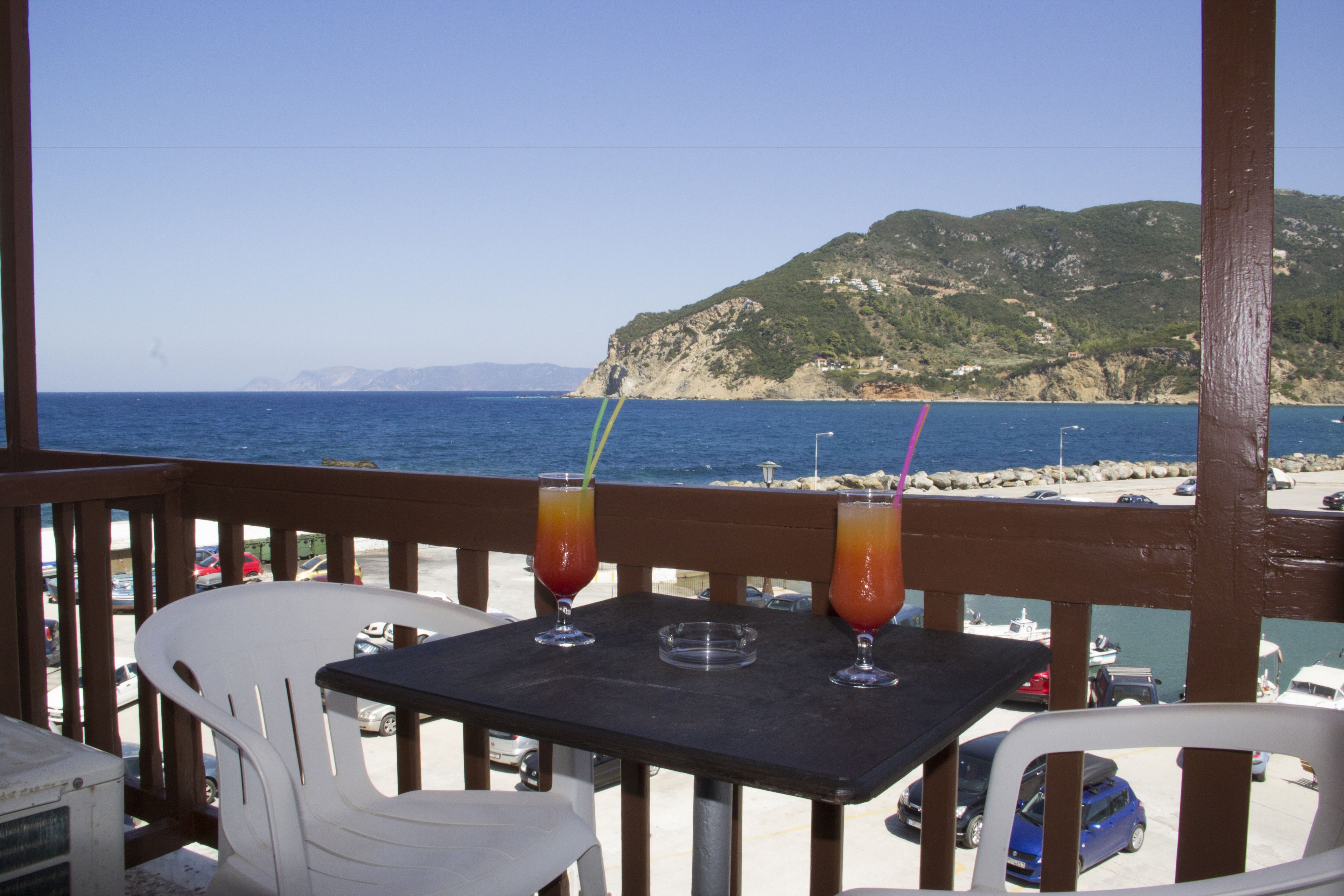 Una mesa con dos bebidas y una silla frente a una vista al mar.