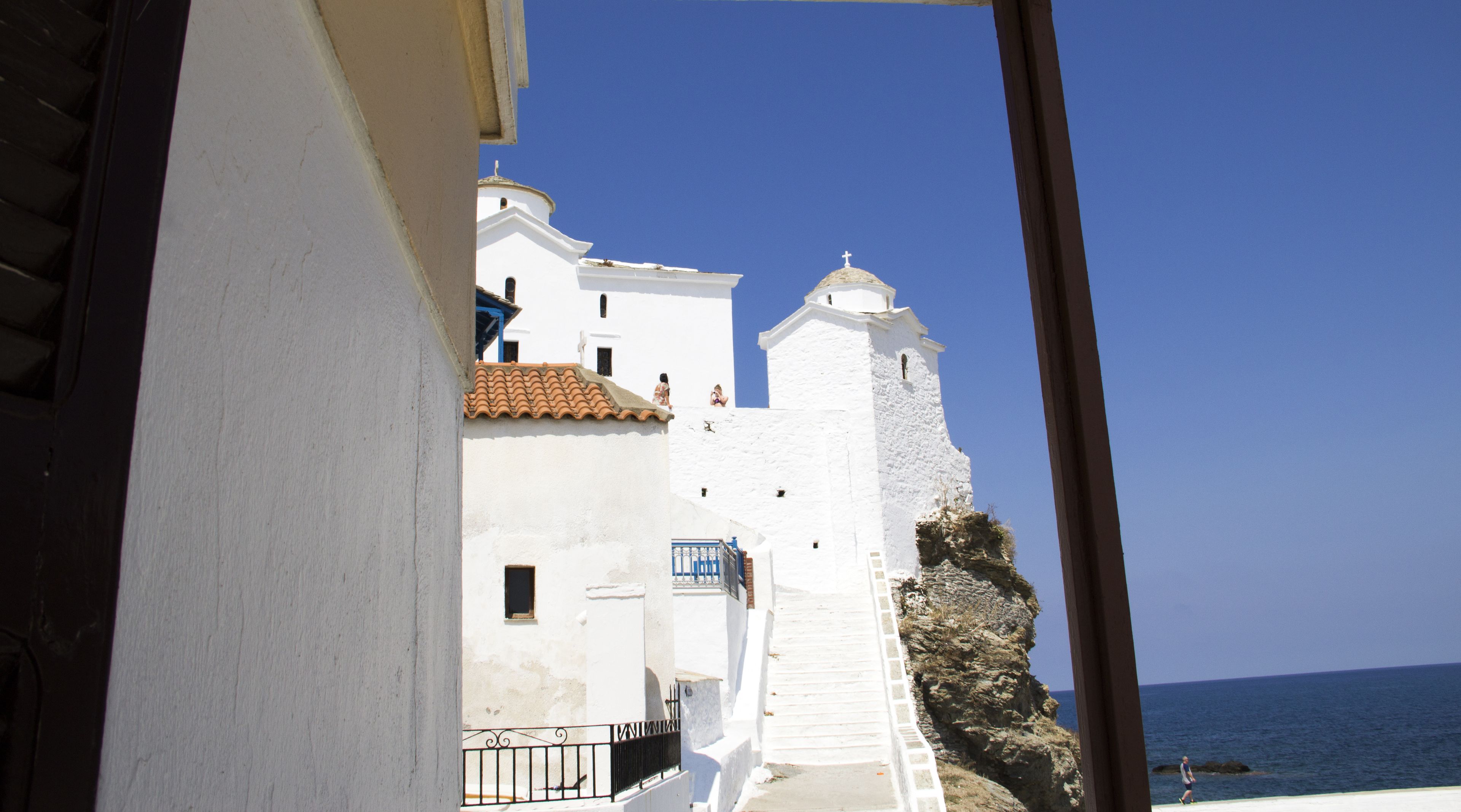 Un edifici costaner amb parets blanques i teulada vermella, amb vista al mar.