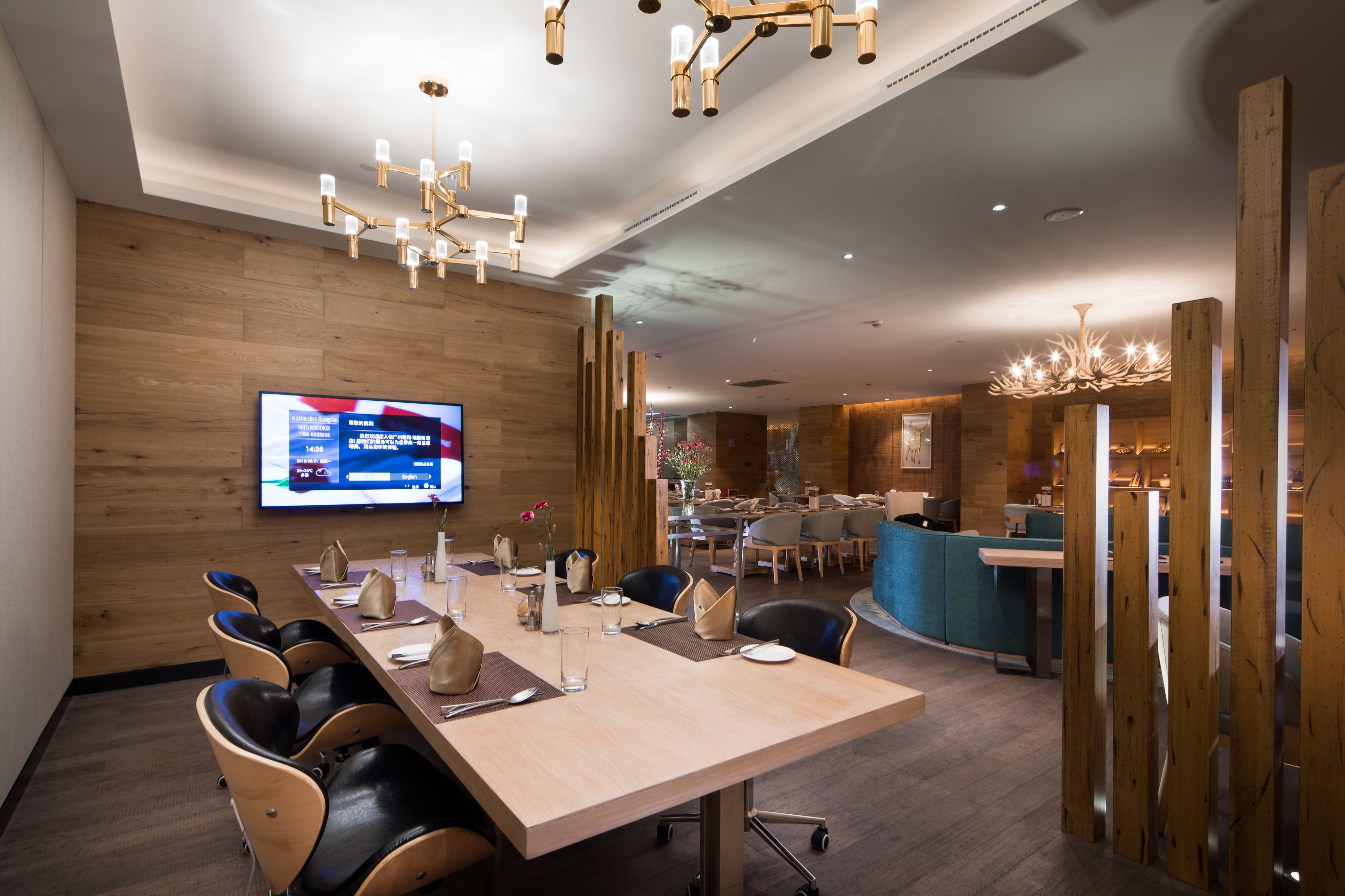 A modern conference room with a long table, comfortable chairs, a flat-screen TV, and a wooden accent wall.