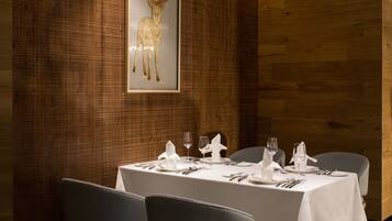 A dining area with a table set for four, chairs, and a framed deer artwork on the wall.