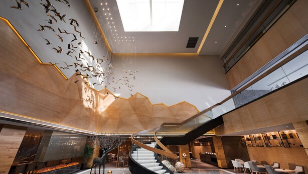 Un hall d’entrée spacieux avec un escalier central, un plafond haut doté d’une verrière et un design moderne.
