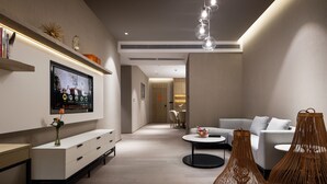 Un salon moderne avec un téléviseur à écran plat, un canapé blanc, une table basse et des lampes en osier.