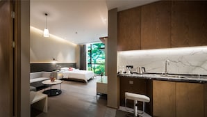 Une chambre d’hôtel moderne comprenant un lit, une table de chevet et un petit coin salon avec un canapé et une table basse.