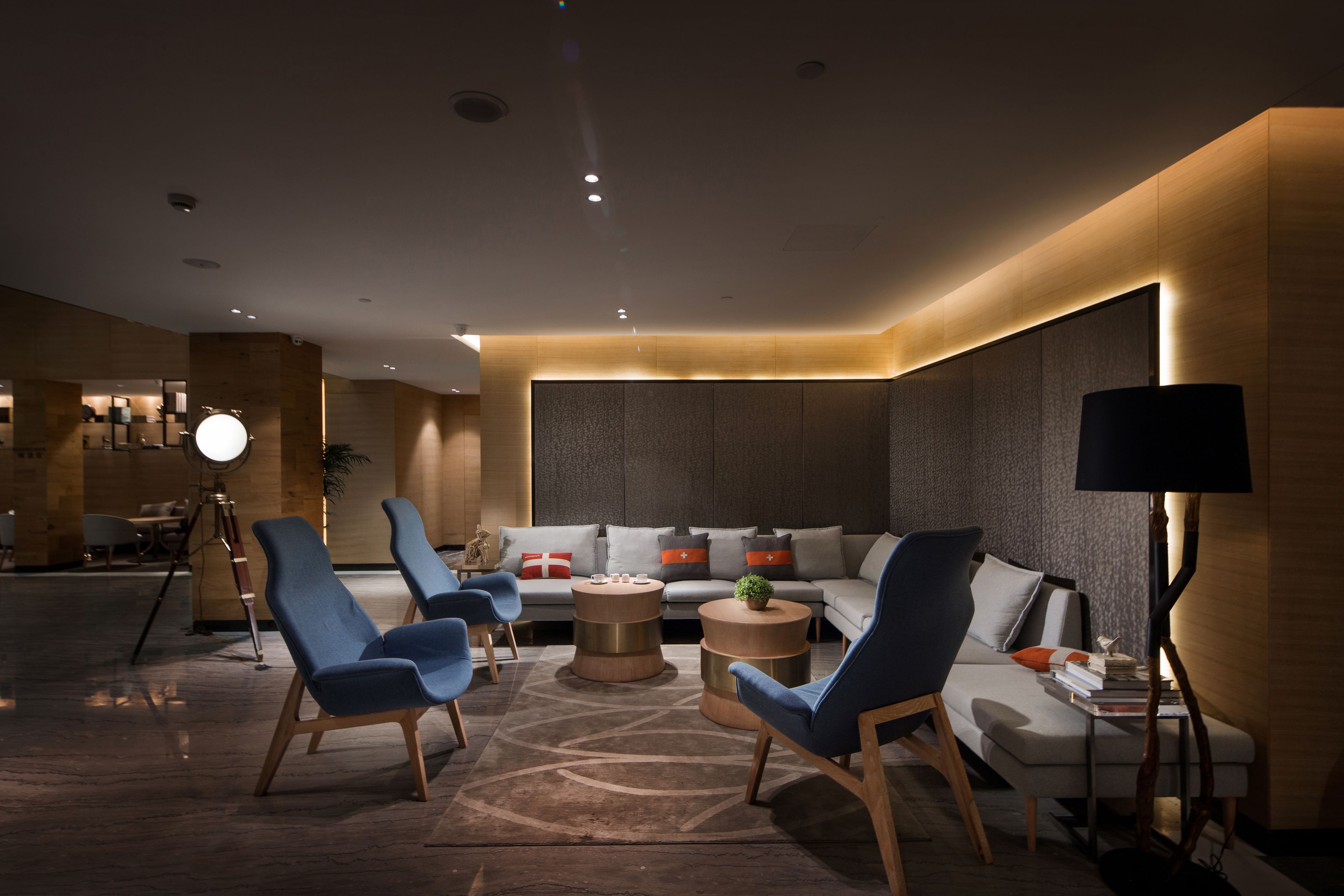 Un hall d’hôtel moderne doté d’un espace salon comprenant des canapés et des fauteuils, une table basse et un lampadaire.