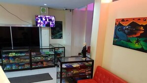 A room with a red sofa, glass display cases with items, a TV, and a painting on the wall. - City Corner Hotel (Legazpi)
