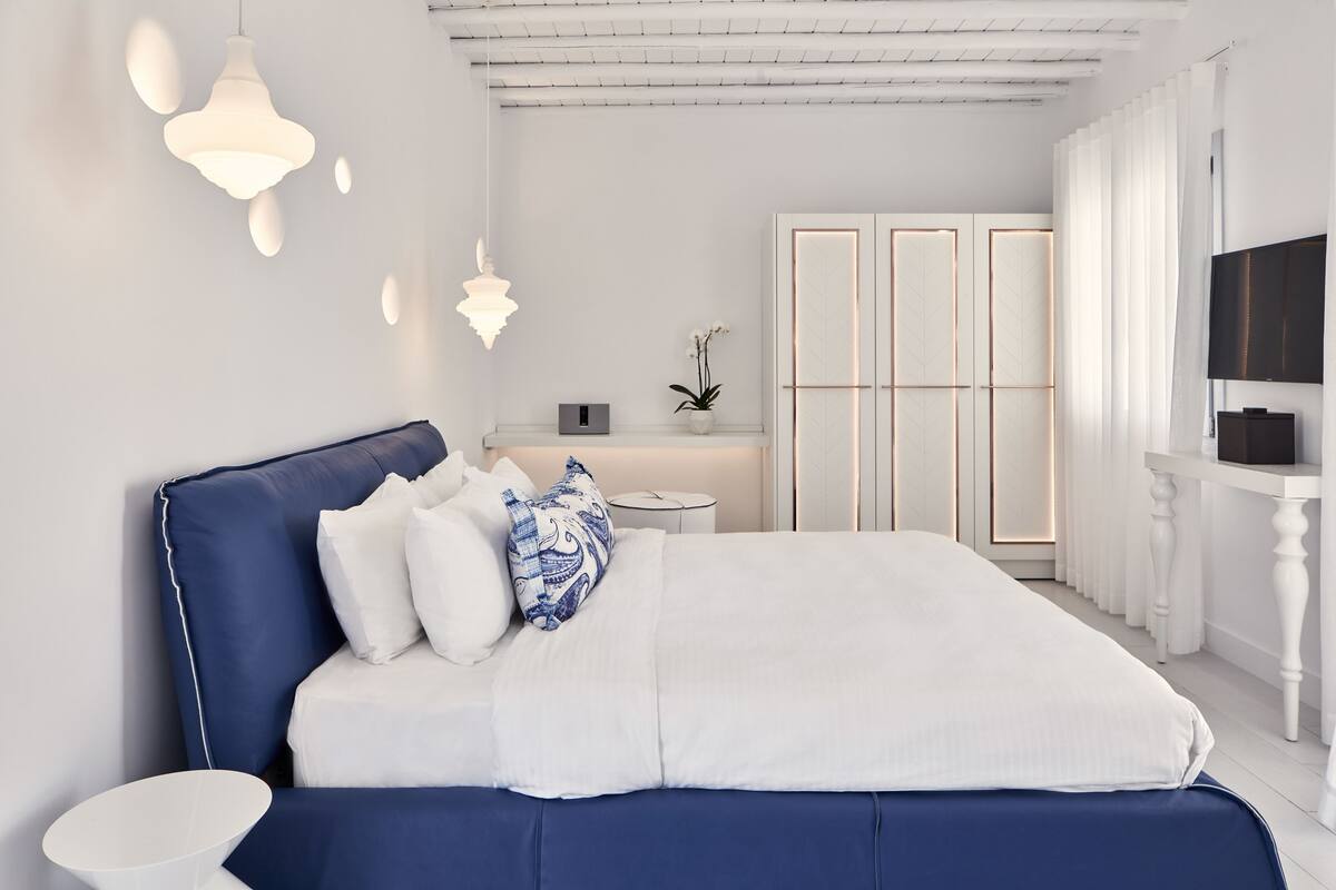 Ein modernes Schlafzimmer mit einem großen Bett, einem Nachttisch, einem Fernseher und einem Kleiderschrank.