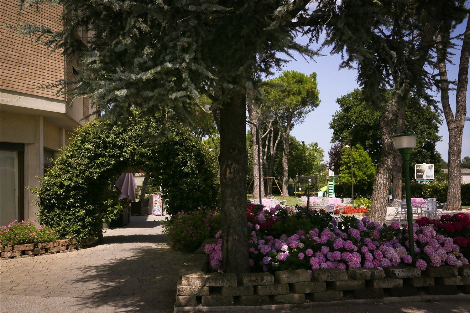 A courtyard with a brick building, trees, and a playground.