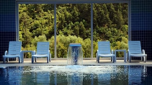 Una piscina techada, una piscina al aire libre, sombrillas