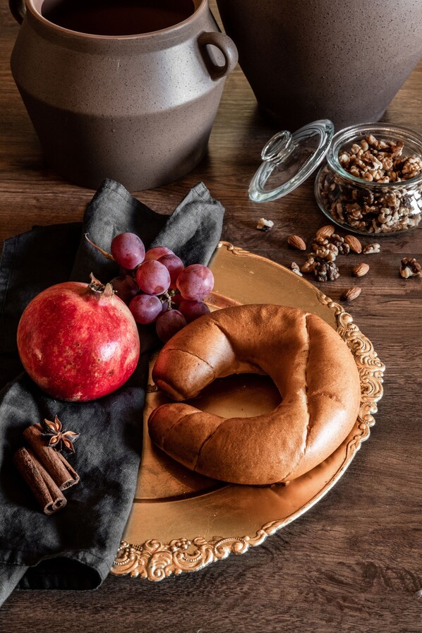 Una mesa rústica con una granada, uvas, un pretzel y una taza de café.