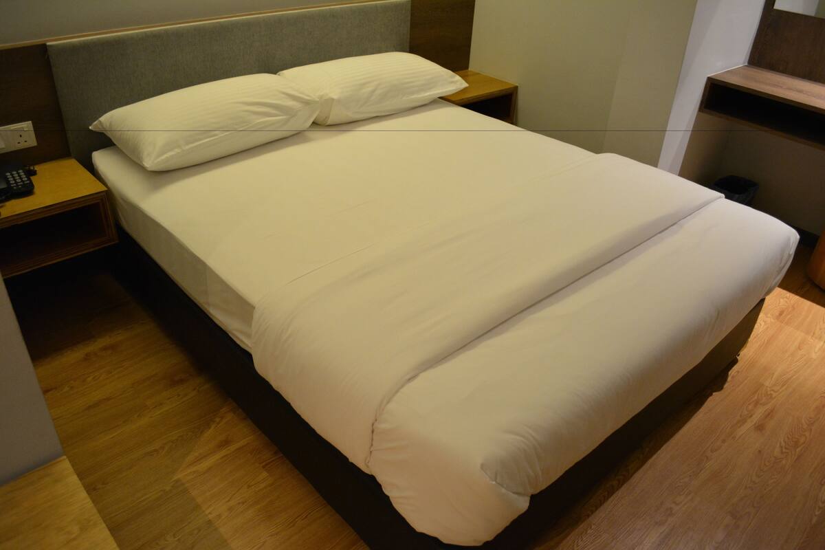 A neatly made bed with white bedding in a hotel room.