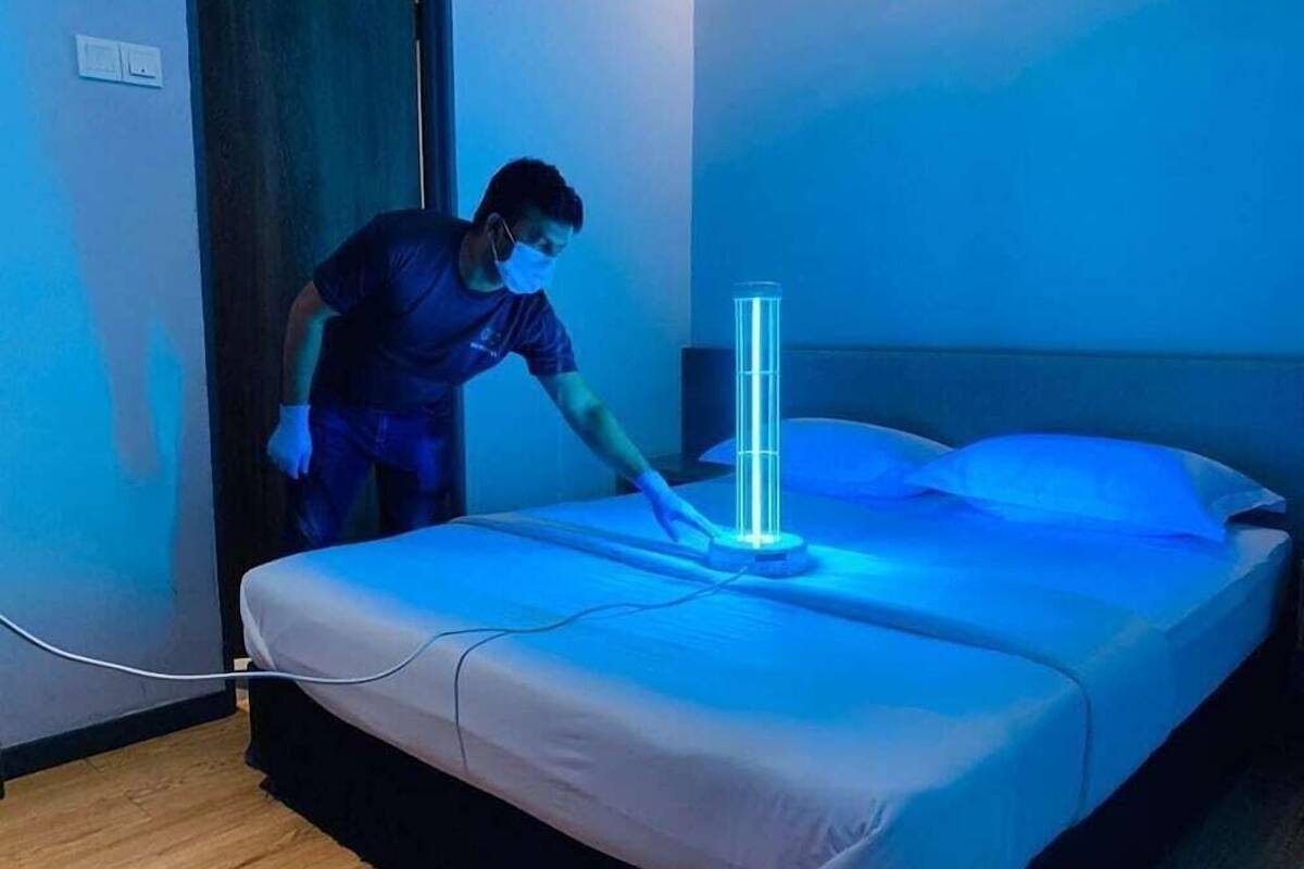 A person adjusting a cylindrical device on a bed in a room with a wooden floor and a blue wall.