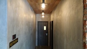 A narrow hallway with a sign indicating a restroom to the left. A door is visible at the end of the hallway.