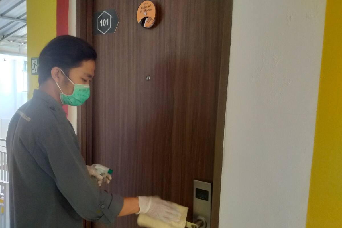 A person wearing a mask and gloves, using a keycard to enter a room with a door marked '101'.