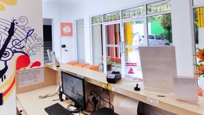 A reception desk with a computer, printer, and a red office chair. - Djo Front One Inn Bengkulu (Bengkulu)