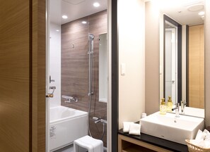 A modern bathroom with a bathtub, shower, and sink. - Hotel Hewitt Koshien (Nishinomiya)