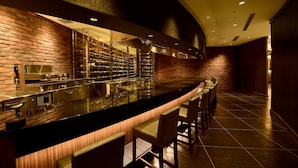 A bar area with a brick wall, stainless steel bar, and seating. - Hotel Hewitt Koshien (Nishinomiya)