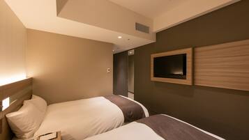 A hotel room with two beds, a TV mounted on the wall, and a bedside table with a phone and a notepad.