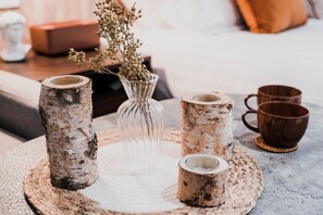Une table avec quatre vases en verre et deux gobelets en bois, le tout posé sur un set de table en fibres tressées.