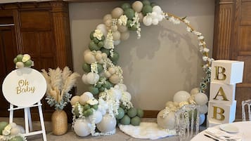 Een feestruimte met decoratie, een bloemenboog en een gedekte tafel voor een formeel evenement.