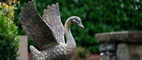 A swan statue in a garden setting.