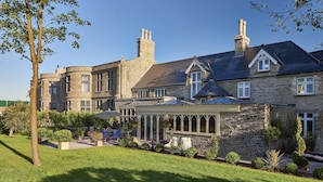 A large stone house with a covered patio and a well-maintained garden. - Lanelay Hall Hotel & Spa (Pontyclun)